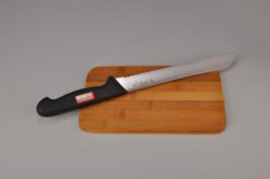 venstrehånds brødkniv med plastik håndtag placeret på et skærebræt
