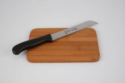 venstrehånds brødkniv med plastik håndtag placeret på et skærebræt